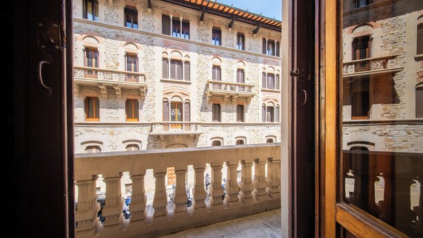A view of a building with multiple balconies and windows, viewed through a wooden door. - Mantellate 9 (Florence)