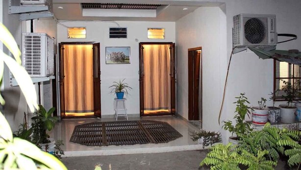 A room with two doors, air conditioning units, a small table with a plant, and potted plants outside. - my homestay jaipur soni2700 (Jaipur)
