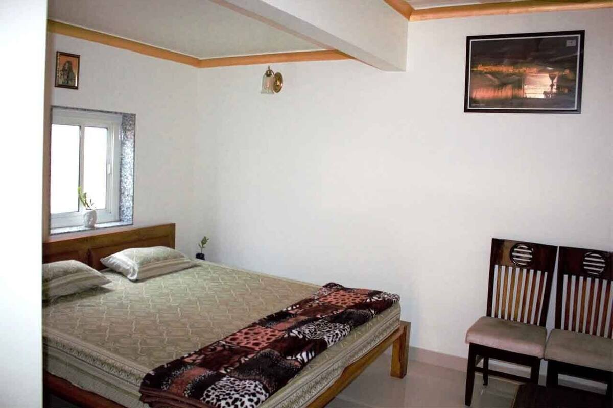 A bedroom with a bed, a window, a chair, and a wall-mounted picture.