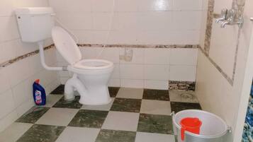 Ein Badezimmer mit Toilette, einem Schachbrettmuster Boden, einem Eimer und einem Reinigungsmittel.