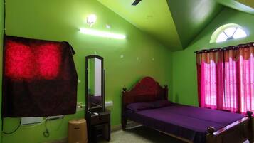A bedroom with a bed, a ceiling fan, a mirror, and a window with curtains.