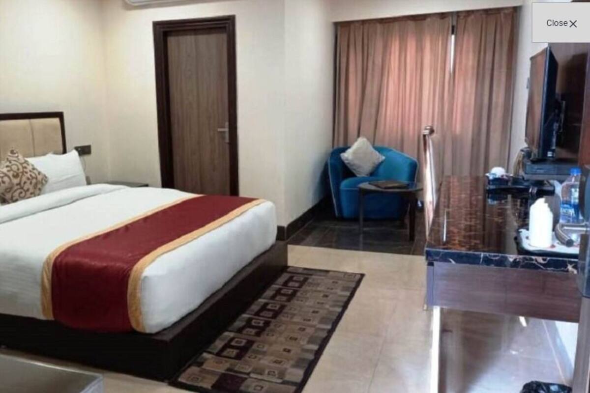 A hotel room with a bed, a sofa, a TV, and a bathroom area.