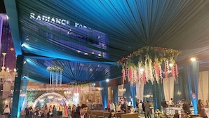 A decorated event space with a chandelier, draped fabric, and floral arrangements. - HOTEL RADIANCE PARK RAMPUR (Rampur)
