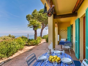 Una mesa dispuesta con platos, vasos y limones en una terraza con vista al mar.