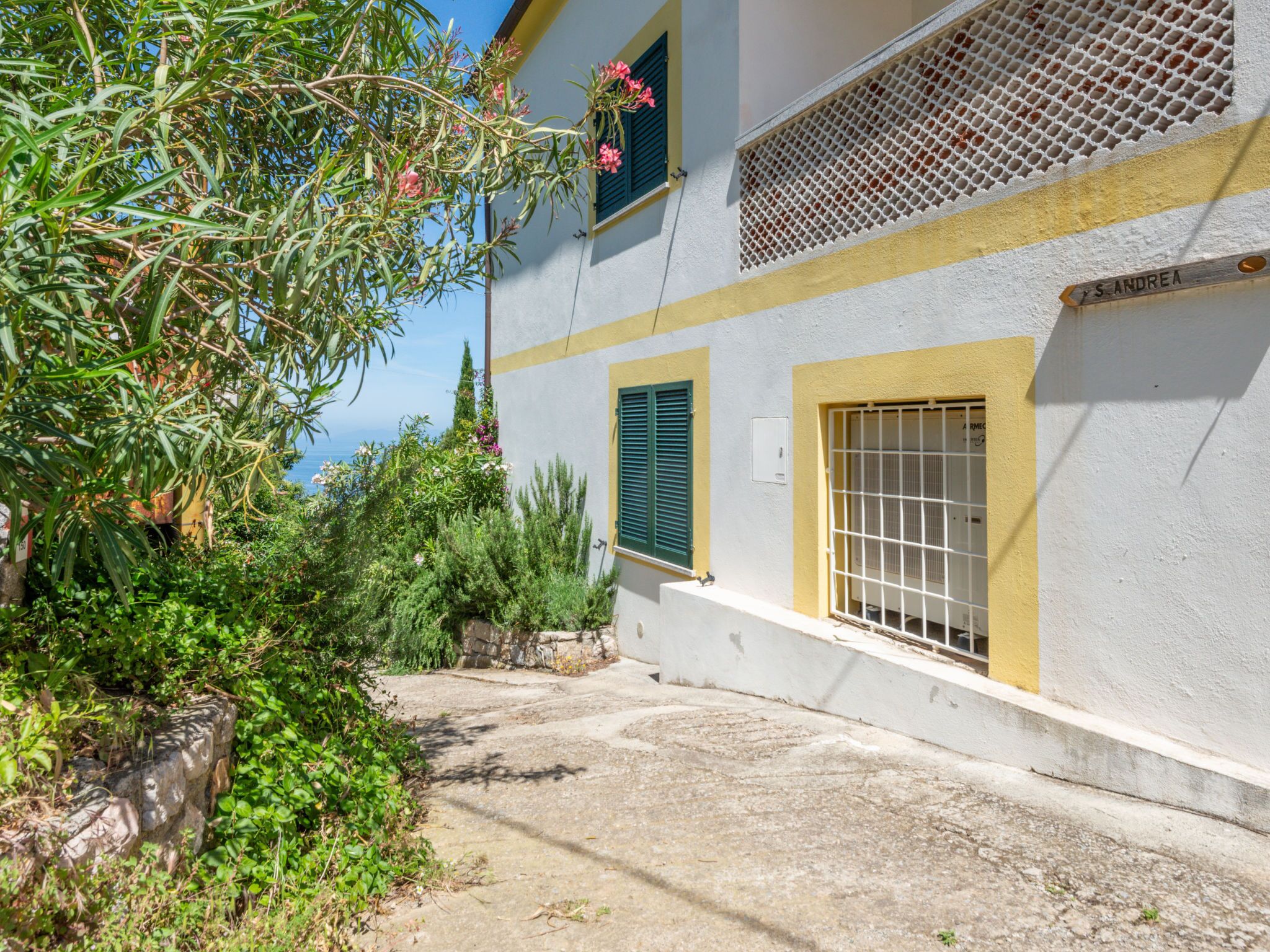 A building with a white facade, green shutters, and a yellow stripe.