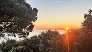 Sonnenuntergangblick von einem Balkon mit einem Metalltank und einer Holzbank.