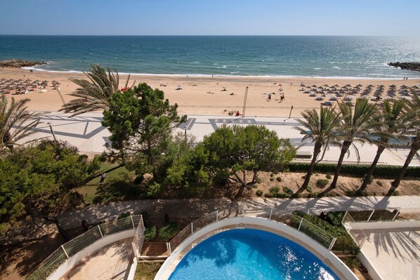 A pool area with a view of a beach and ocean.