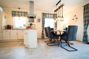 Uma cozinha moderna com armários brancos, uma ilha central e um espaço de jantar com mesa e cadeiras.