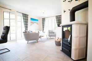 A modern living room with a fireplace, a sofa, a chair, and a dining area.