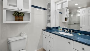 A modern bathroom with a white toilet, a blue countertop sink, and white cabinets. - Coastal Getaway: Oceanfront Dune King Room (Pawleys Island)