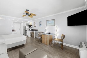 A modern living room with a sofa, a dining table, and a TV mounted on the wall.