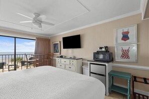 Una habitación de hotel con cama, escritorio, televisor y obras de arte en la pared.