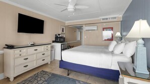 Een hotelkamer met een bed, een bureau, een televisie en een plafondventilator.