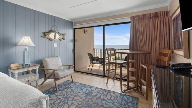 Een hotelkamer met een bed, een bureau, een stoel, een tafel en een balkon met uitzicht.