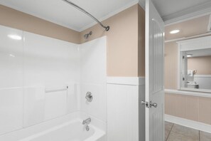A bathroom with a bathtub, a shower, and a mirror.
