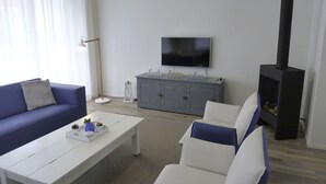Una sala de estar con sofá, mesa de centro, televisor, mueble y chimenea.
