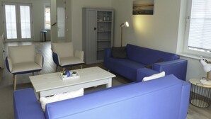 Una sala de estar moderna con un sofá azul, una mesa de centro blanca y un aparador gris.