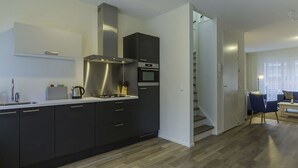 Una cocina moderna con armarios oscuros, una campana extractora de acero inoxidable y un horno empotrado.