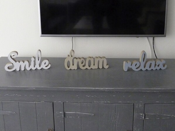 Un letrero en la pared con la inscripción 'Smile dream relax' sobre un gabinete gris.
