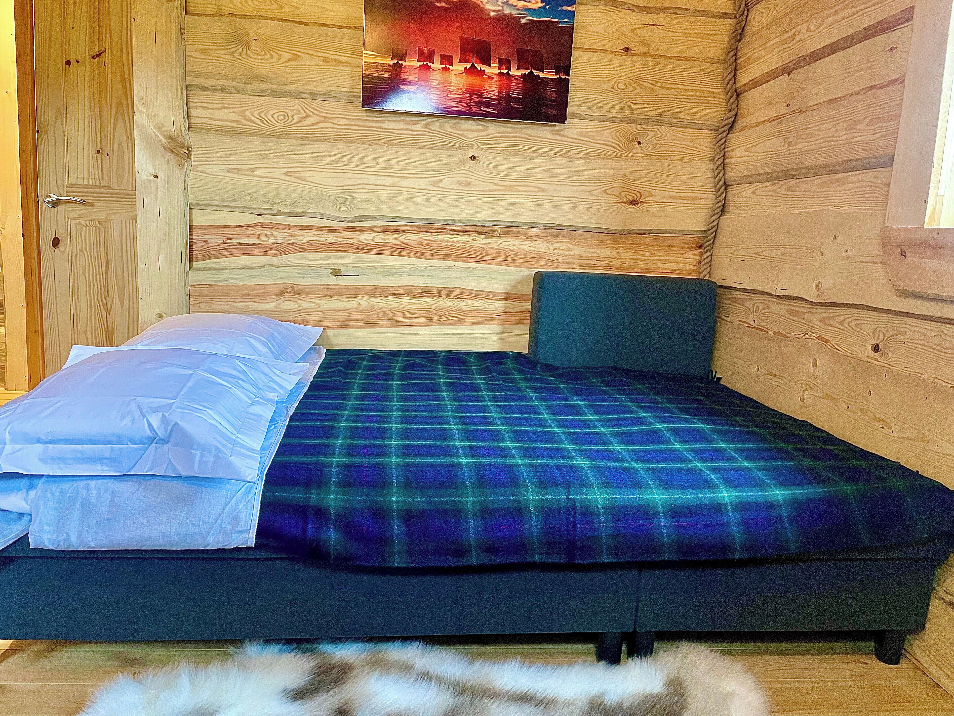Een kleine houten kamer met een bed, een kussen en een deken.