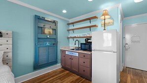 A compact kitchen with a refrigerator, microwave, and wooden shelves. - Beaches and Waves Resort View 2nd Floor (Pawleys Island)