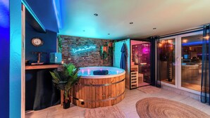 A modern bathroom with a wooden bathtub, a neon sign, and a brick wall.