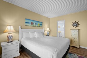 Une chambre à coucher comprenant un lit, des tables de chevet, une lampe, un tableau, un miroir et une armoire.