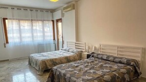 Un dormitorio con dos camas, una ventana con cortinas y un ventilador de techo.