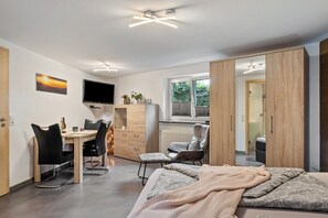 Une chambre moderne équipée d’un lit, d’un bureau, d’une chaise et d’un téléviseur.