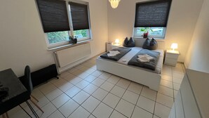 Une chambre à coucher comprenant un lit, des tables de chevet, un bureau et une chaise.