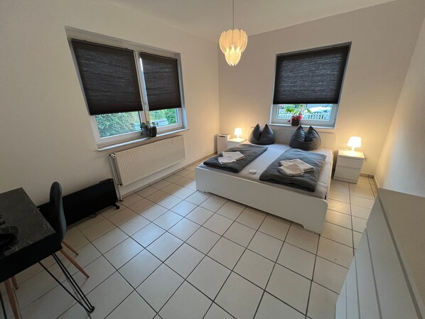 Une chambre à coucher comprenant un lit, des tables de chevet, un bureau et une chaise.