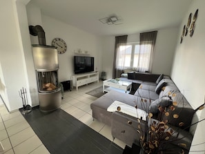 A living room with a fireplace, sofa, TV, and a dining area with a table and chairs.