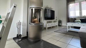 Un salon moderne doté d’une cheminée, d’un téléviseur à écran plat, d’un canapé et d’un coin repas.