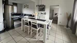 A modern kitchen with a dining area, a built-in oven, and a refrigerator. - Holiday Home 'Almir' with Private Terrace, Private Garden and Wi-Fi (Haselünne)