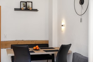 A dining area with a wooden table, black chairs, and a bowl of oranges.