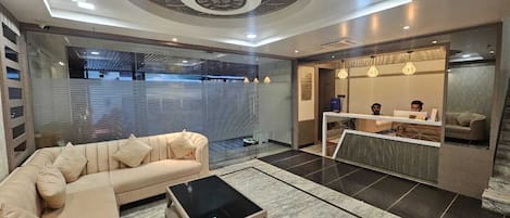 Een moderne hotellobby met een bank, een bijzettafeltje, een receptiebalie en een gestreept plafond.