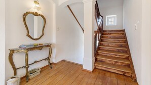 Eine Treppe mit Holzdielen und Geländer, ein an der Wand befestigter Spiegel und ein Konsolentisch mit Büchern und einem Korb.