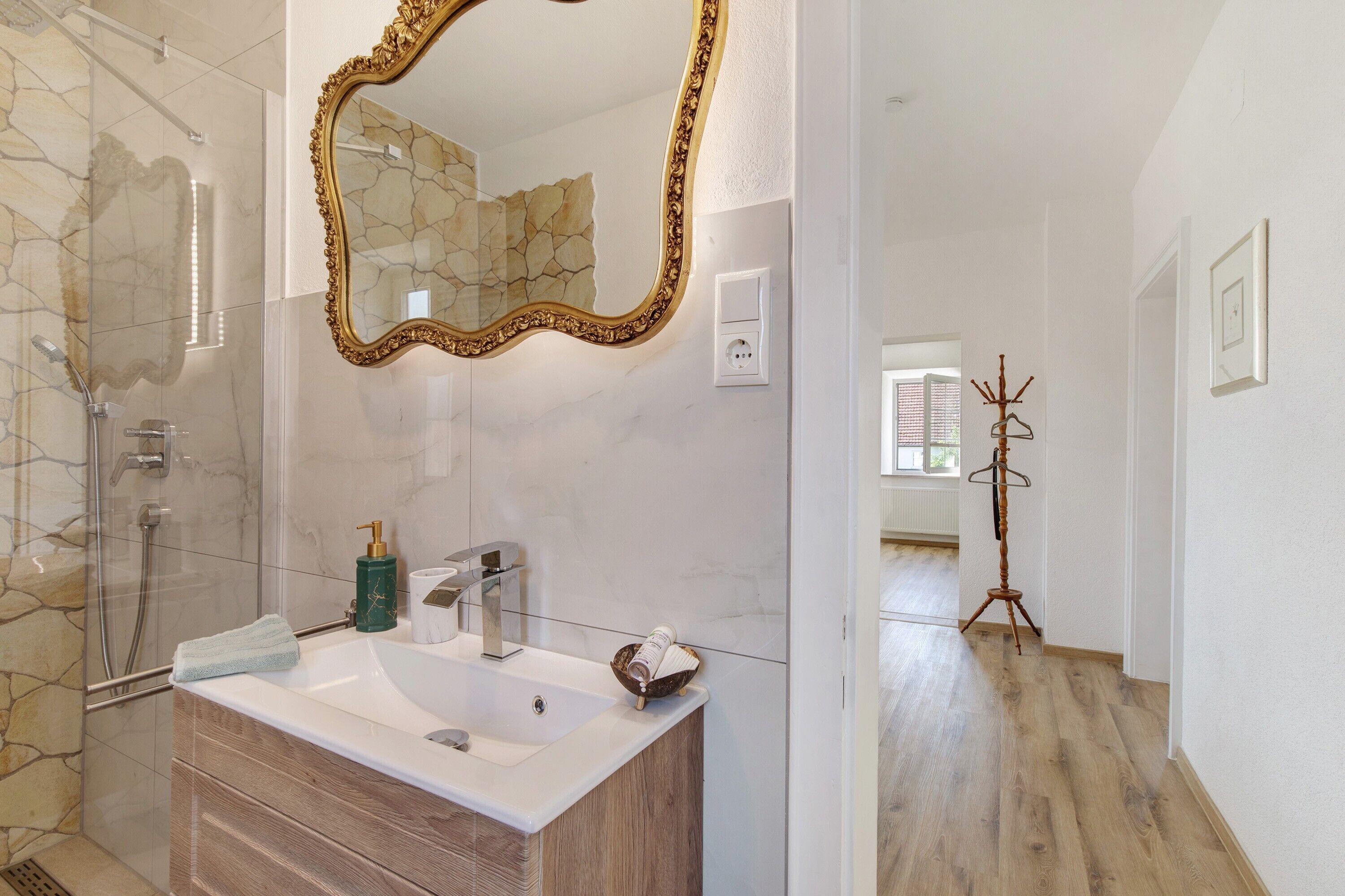 Un baño con un espejo grande, un lavabo y una ducha.