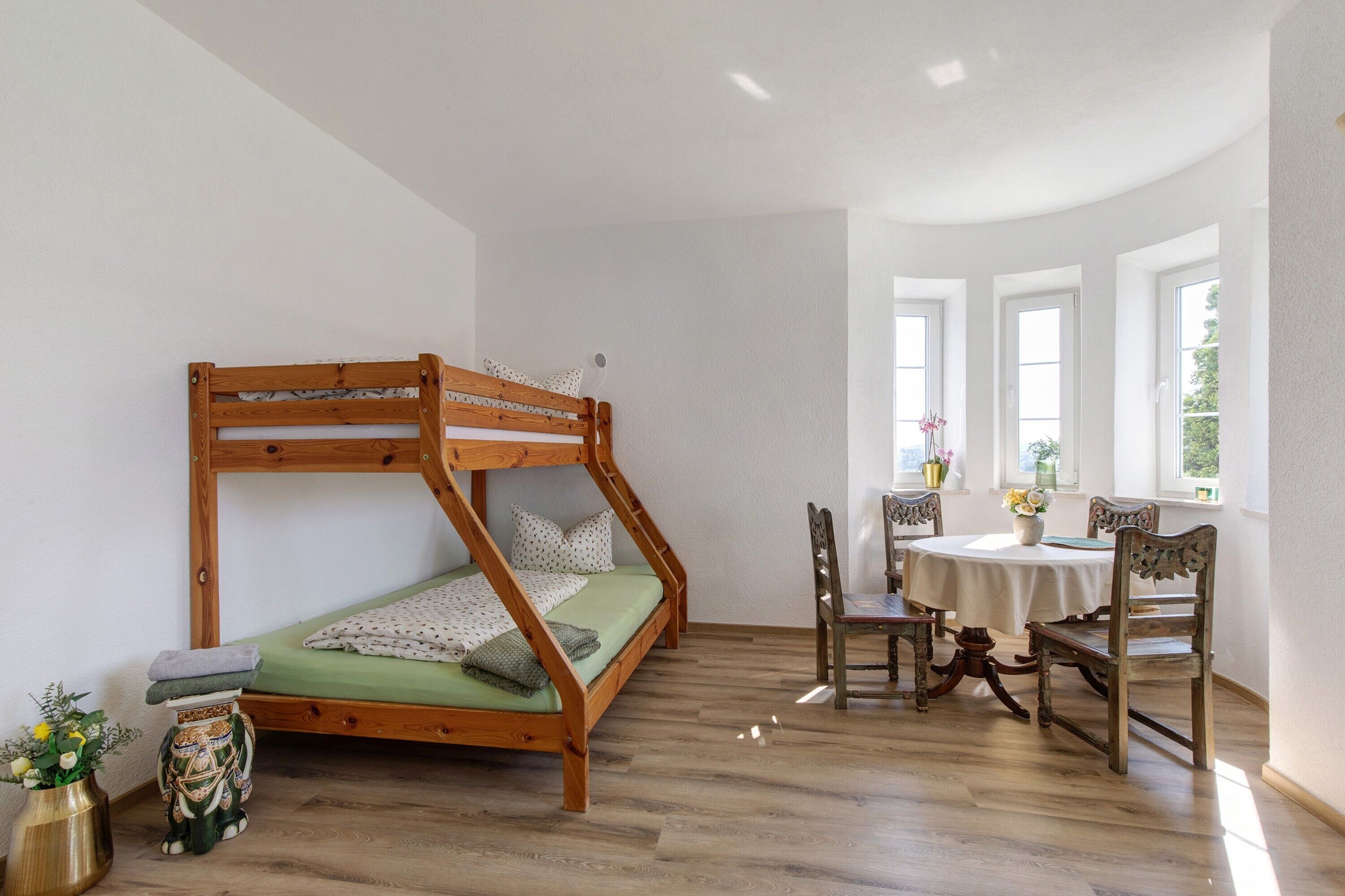 Ein Zimmer mit einem Etagenbett, einem Esstisch mit Stühlen und einem Fenster mit Blick.
