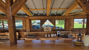 Ein rustikales Holzinterieur mit einem langen Tisch, einer Spüle und Blick ins Freie.