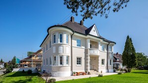 Ein großzügiges, zweistöckiges Haus mit einer geschwungenen Fassade, zahlreichen Fenstern und einem gepflegten Rasen.
