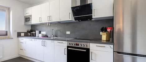 A modern kitchen with white cabinets, stainless steel appliances, a microwave, oven, and a dishwasher.