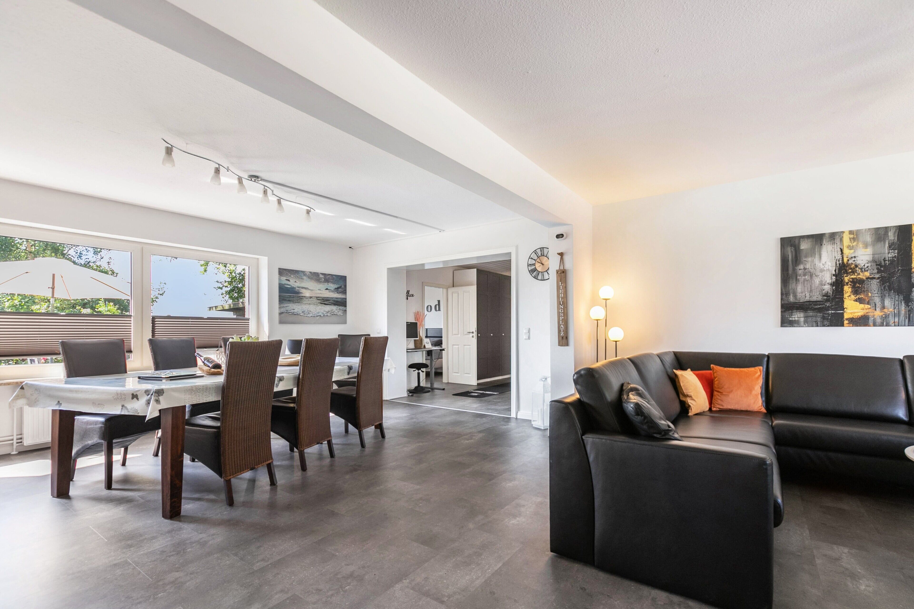 A modern interior with a dining area, a black leather sofa, and a large window.