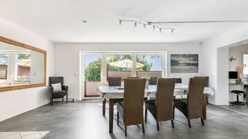 A dining area with a table and chairs, a large mirror, and a view of the outdoors through a sliding door.
