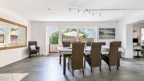 Un comedor con mesa y sillas, un espejo grande y vista al exterior.
