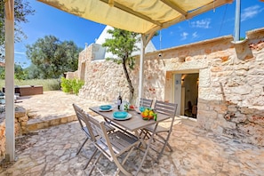 Un espacio exterior para comer con paredes de piedra, una mesa cubierta y sillas.