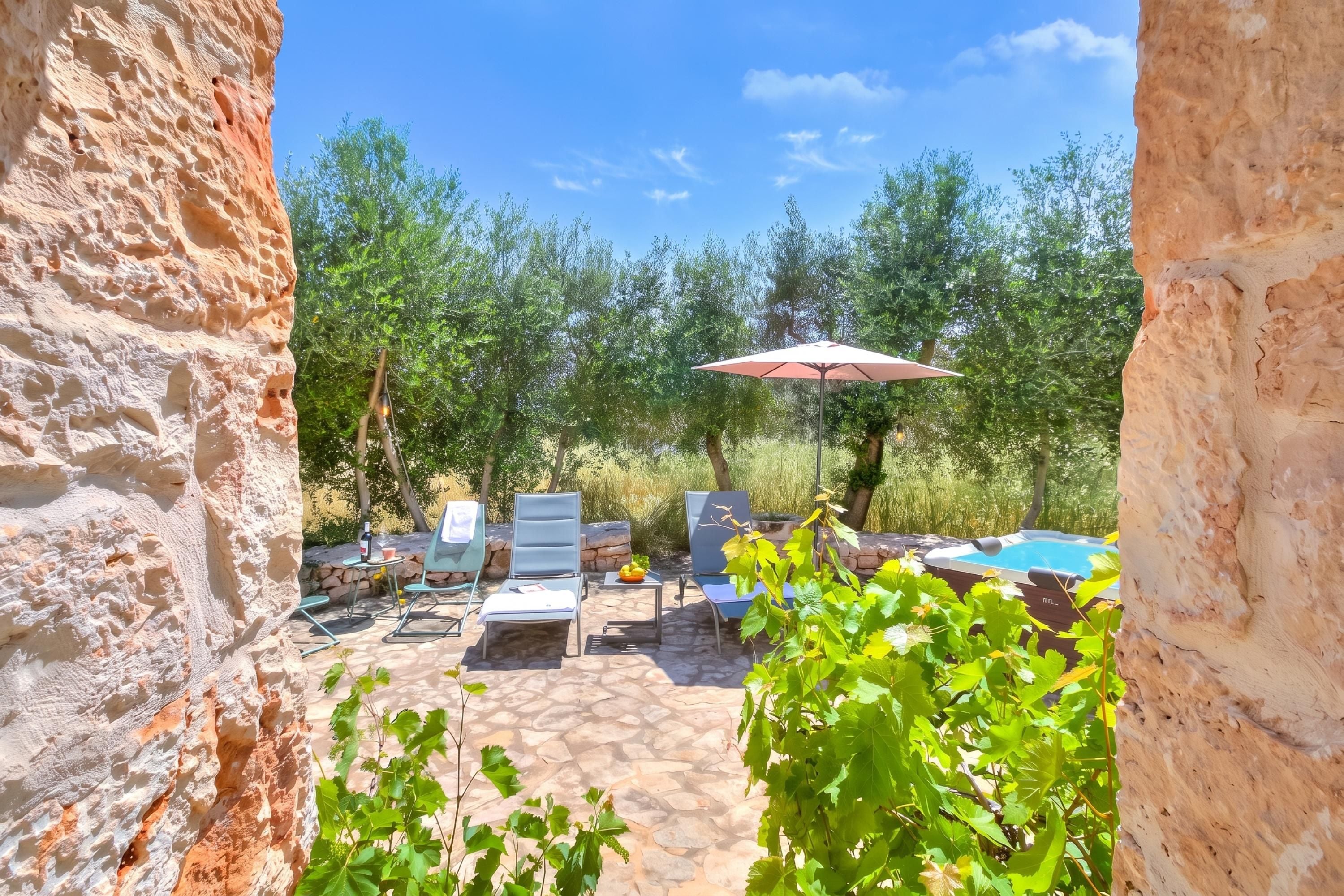 Un patio in pietra con mobili da esterno, una piscina e vegetazione lussureggiante.