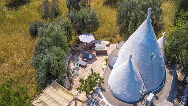 Luchtbeeld van een gebouw met een uniek kegelvormig dak, omgeven door een stenen terras en buitenmeubilair.