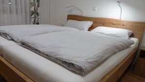 Ein ordentlich bezogenes Bett mit weißen Leinen und einem hölzernen Kopfteil.