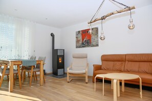 Ein Wohnzimmer mit Sofa, Sessel, Tisch und Kamin.